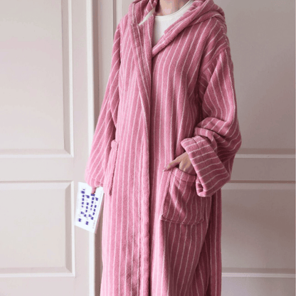 Person wearing a pink striped robe with a hood in a neutral setting