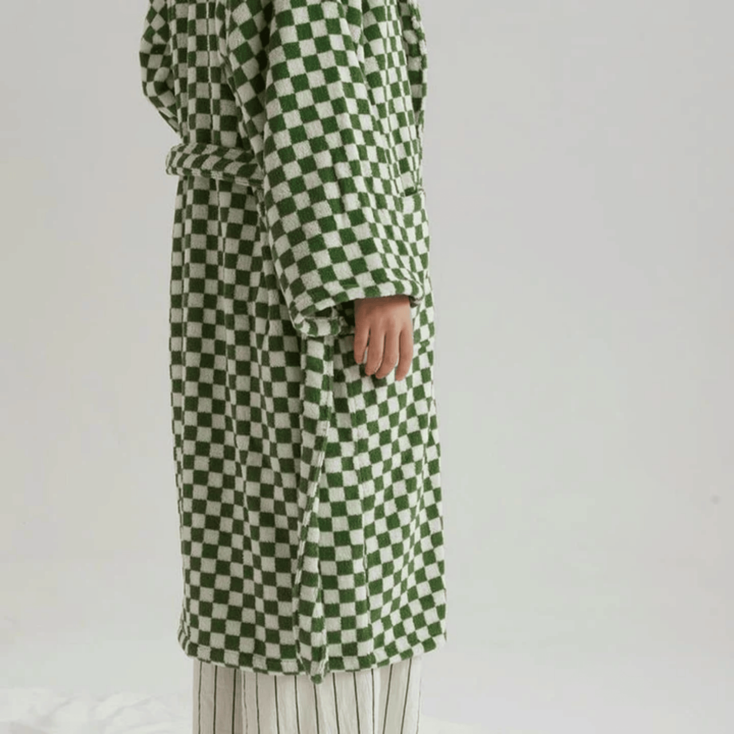 Green and white checkered coat worn by a person on a plain background