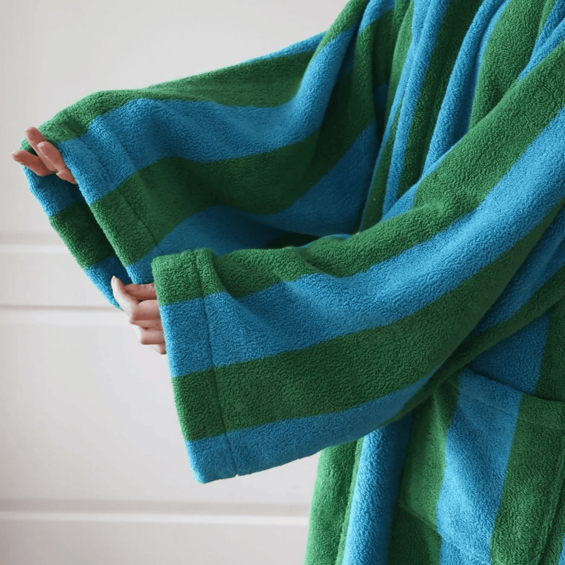 Green and blue striped towel being held against a white background