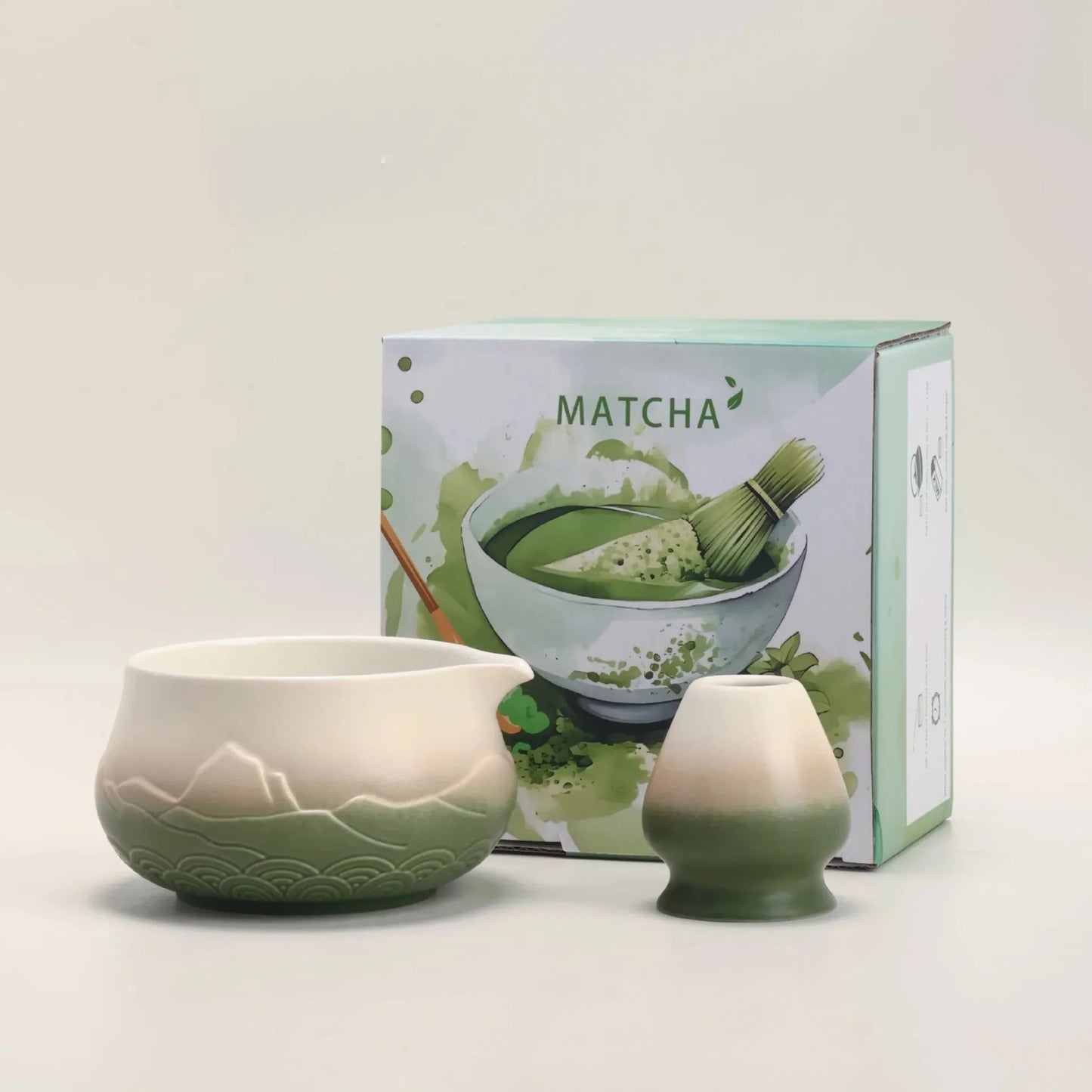 Ceramic matcha bowl and whisk set with a matcha-themed box on a light background