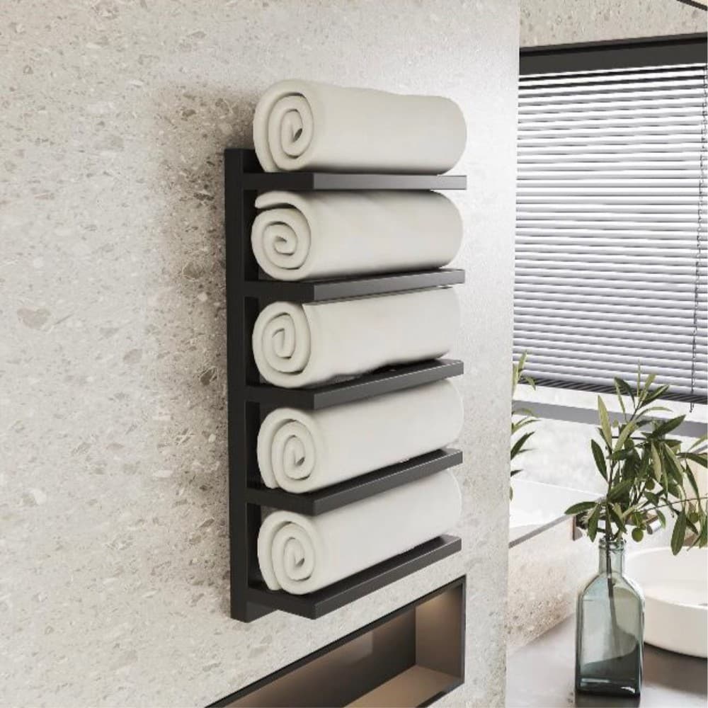 Wall-mounted black towel rack with five tiers, holding rolled white towels in a modern bathroom with light beige walls and a nearby plant by the window.