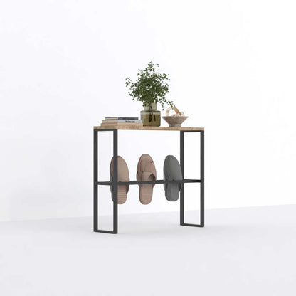 A black metal and wood-top slipper rack, shown in a minimalistic setup with slippers and decorative accents, placed against a bright white background.