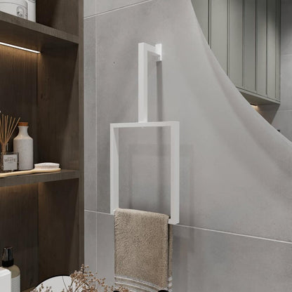 A minimalist white-finished vertical towel ring is mounted on a light gray wall. The modern rectangular design holds a beige towel, adding a clean and stylish touch to the bathroom decor. The sleek towel ring enhances the minimalist aesthetic of the space, perfectly complementing the surrounding neutral tones and simple design elements.