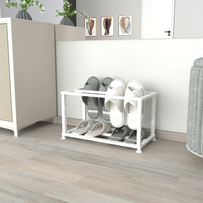 A sleek white metal slipper stand on a wooden floor near a white cabinet and decorative accents, holding multiple pairs of gray and white slippers