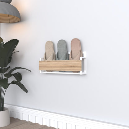 A white wall-mounted slipper rack with a wooden front, designed for compact and elegant storage, holding three pairs of slippers in soft pastel tones